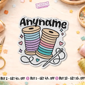 May include: An embroidered patch featuring two spools of thread with horizontal stripes in shades of blue, purple, pink, and teal. The word Anyname is stitched in black above the spools, accompanied by a sewing needle and small heart icons.