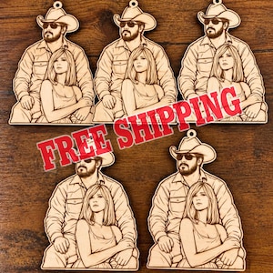 May include: Five identical laser-cut wooden ornaments featuring a line-art illustration of a man in a cowboy hat and sunglasses sitting behind a woman with shoulder-length hair. Each piece has a small hole at the top for hanging.