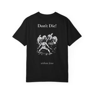 Op de afbeelding: Zwart t-shirt met een witte afbeelding van een persoon die vier dieren confronteert. De tekst "Don't Die!" staat boven de illustratie, met "without Jesus" eronder.