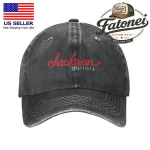 Puede incluir: Una gorra de b&eacute;isbol gris carb&oacute;n con las palabras "Jackson guitars" bordadas en rojo. La gorra tiene una visera curva y un aspecto vintage descolorido. El sombrero tiene el logotipo "Fatonei Custom Hats".