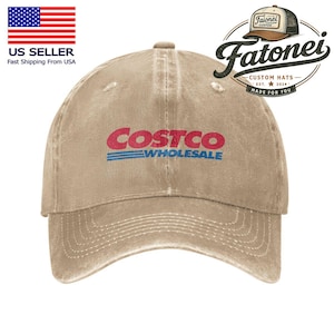 以下が含まれることがあります： 赤と青のCostco Wholesaleのロゴが入ったベージュ色の野球帽。帽子はつばがカーブしており、使い古したような外観です。帽子はFatonei Custom Hats製です。