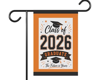 May include: A rectangular garden flag hanging on a black metal stand. The flag features an orange border, a white centre, and black text reading Class of 2026 GRADUATE The Future is Yours, accompanied by two black graduation cap icons and stars.