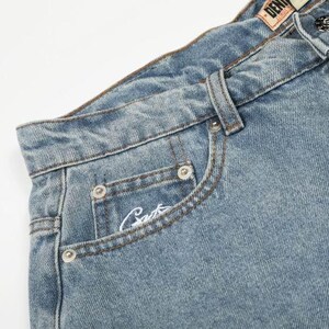 Peut inclure: Jean en denim bleu clair avec une taille haute, une fermeture &agrave; bouton m&eacute;tallique, des passants de ceinture et une petite poche gousset. La poche gousset pr&eacute;sente une inscription brod&eacute;e en blanc et la ceinture porte une &eacute;tiquette en similicuir.