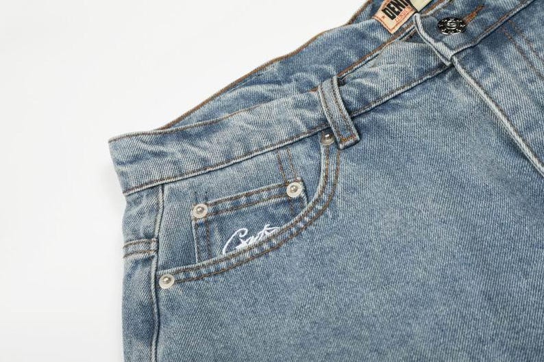 Peut inclure: Jean en denim bleu clair avec une taille haute, une fermeture &agrave; bouton m&eacute;tallique, des passants de ceinture et une petite poche gousset. La poche gousset pr&eacute;sente une inscription brod&eacute;e en blanc et la ceinture porte une &eacute;tiquette en similicuir.