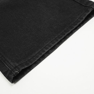 May include: A close-up view of the hem of a black denim garment. The fabric features a visible twill weave texture with sturdy, tonal stitching along the folded edge. The material appears to be a durable cotton denim with a matte finish.