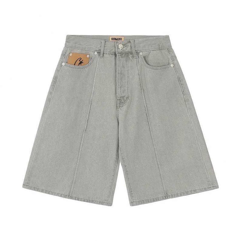 May include: Light gray denim shorts featuring a high-waisted design with a button and zipper fly closure. The shorts include vertical seam detailing down the front, two side pockets, and a small tan leather-like patch with a black star logo.
