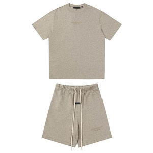 May include: A light heather gray short-sleeve t-shirt and matching shorts set. The t-shirt features a small centered logo on the chest. The shorts have an elastic waistband with long white drawstrings and a small logo on the lower left leg.