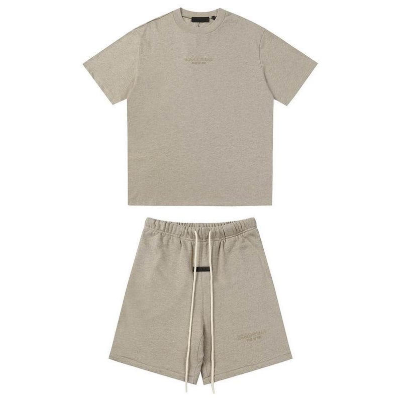 May include: A light heather gray short-sleeve t-shirt and matching shorts set. The t-shirt features a small centered logo on the chest. The shorts have an elastic waistband with long white drawstrings and a small logo on the lower left leg.