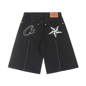 May include: Black denim shorts featuring a high-waist design with a tan leather patch on the back waistband. The back pockets are embroidered with a white stitched letter C and a star on the left, and a large white star on the right pocket.
