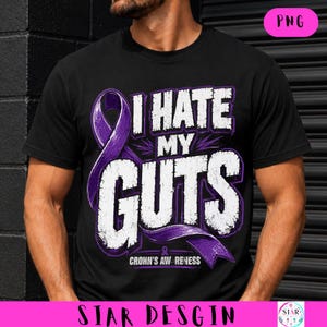 Op de afbeelding: Zwart T-shirt met de tekst "I HATE MY GUTS" in wit en paars, met een paars lint en de woorden "Crohn's Awareness". Het shirt heeft een ronde hals.
