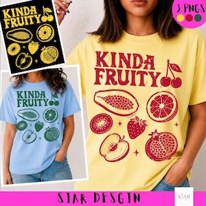 May include: A yellow t-shirt with the text "KINDA FRUITY" in red, along with illustrations of various fruits. A light blue t-shirt with the same design is also shown. The design includes a papaya, orange, kiwi, strawberry, apple, and pomegranate.