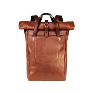 May include: A cognac-coloured leather roll-top backpack featuring a large front pocket, two top carry handles, and a central vertical strap with a metal buckle closure. The design includes adjustable shoulder straps and visible metal rivets.
