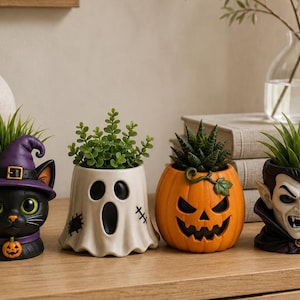 May include: A set of four ceramic planters featuring Halloween characters: a black cat wearing a purple witch hat, a white ghost with black facial features, an orange jack-o'-lantern, and a vampire with a high collar, each holding a small green plant.