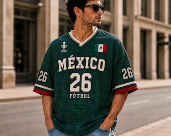 Puede incluir: Una camiseta de cuello en V verde oscuro con el texto MÉXICO 26 FÚTBOL en blanco, un icono de trofeo, el número 26 en las mangas y un parche de la bandera de México en el pecho. La tela presenta un patrón tonal sutil con motivos complejos.