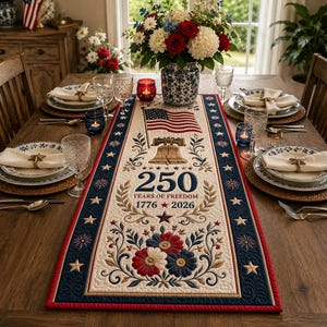 Könnte beinhalten: Ein patriotischer Tischläufer mit cremefarbenem Hintergrund, der eine amerikanische Flagge, die Liberty Bell und den Text "250 Years of Freedom 1776-2026" zeigt. Der Läufer hat einen marineblauen Rand mit Sternen und roten Zierleisten.