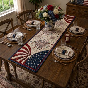 May include: A quilted table runner featuring a patriotic design with red, white, and blue fireworks, stars, and stripes. The runner is centered on a wooden dining table set with plates, napkins, glassware, and a floral centerpiece in a vase.