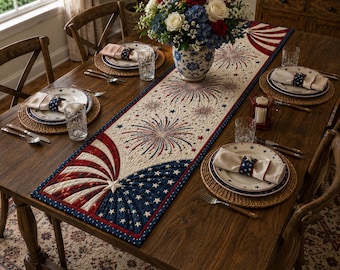 Puede incluir: Un camino de mesa acolchado con un diseño patriótico de fuegos artificiales, estrellas y rayas en rojo, blanco y azul. El camino está centrado en una mesa de comedor de madera con platos, servilletas, cristalería y un centro de mesa floral.