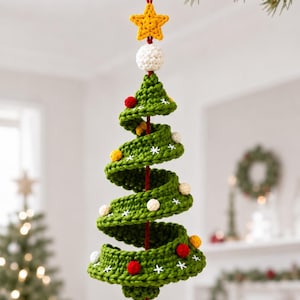 Può includere: Una decorazione natalizia a forma di albero a spirale realizzato all'uncinetto in verde, con una stella gialla in cima, una sfera bianca e piccoli pon pon rossi, gialli e bianchi. L'albero presenta motivi ricamati a fiocco di neve bianchi.
