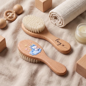 Könnte beinhalten: Zwei Haarbürsten aus Holz mit weichen, hellen Borsten. Eine Bürste ist mit dem Namen Lucy in schwarzer Schreibschrift und einem kleinen Herz graviert. Die andere Bürste zeigt eine bunte Grafik eines Einhorns auf einer blauen Wolke mit Sternen.