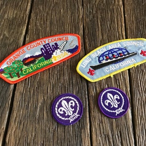 May include: Two Boy Scout patches with the text "Orange County Council California" and "Long Beach Area Council California" and two purple Boy Scout fleur-de-lis patches.