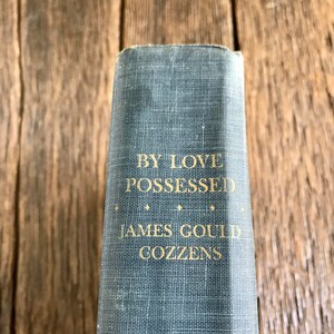 May include: A blue hardcover book with the title "By Love Possessed" and the author "James Gould Cozzens" printed in gold lettering.
