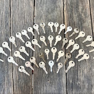 May include: A collection of silver keys arranged in a fan shape on a weathered wooden surface.