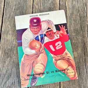 May include: Vintage official program cover featuring a football game illustration. The cover shows two football players in action, one in a red jersey with the number 12. The program is for Washington U. vs Boston U., dated October 17, 1936.