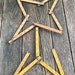May include: Six vintage wooden folding rulers arranged in a star shape on a weathered wooden surface. The rulers are yellowed with age and have black markings.