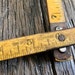 May include: A close-up of a wooden ruler with markings in inches and centimeters. The ruler is labeled "Made in Czechoslovakia" and has the numbers 4, 5, and 6 visible. The ruler is resting on a weathered wooden surface.