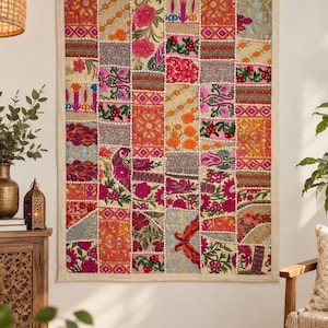 May include: A rectangular wall hanging featuring a patchwork design of various embroidered fabric squares. The textile displays a vibrant array of colors including pink, orange, gold, and green, with intricate floral and geometric patterns throughout.