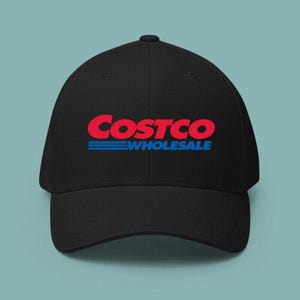 May include: Black baseball cap featuring the Costco Wholesale logo in red and blue. The cap has a curved brim and a structured fit. The text "Costco" is in a bold, red font, with "Wholesale" in blue below.