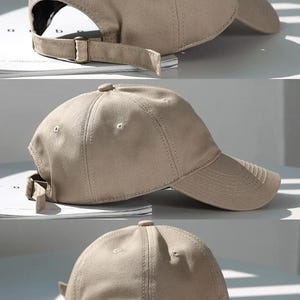 May include: A tan baseball cap with a curved brim and adjustable strap. The cap is made of a solid-colored fabric and features a structured crown with a button on top. The adjustable strap has a metal buckle.