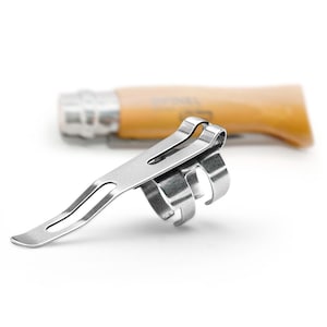 May include: A silver-colored pocket knife clip with a curved design, featuring a slotted end and three curved finger grips. A wooden-handled pocket knife is slightly out of focus in the background.