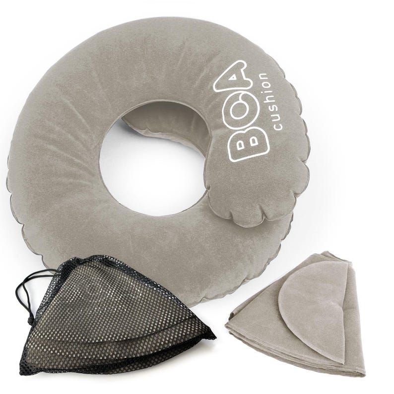 May include: A gray inflatable travel pillow with the word "BOA" and "cushion" printed in white. Includes a black mesh storage bag and a folded gray cover. The pillow is designed for neck support.