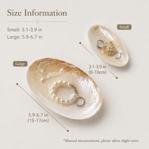 May include: Two oval-shaped mother-of-pearl shell dishes for jewelry. The small dish measures 3.1-3.9 inches and holds a gold-toned floral charm. The large dish measures 5.9-6.7 inches and contains a white pearl bracelet and a silver ring.
