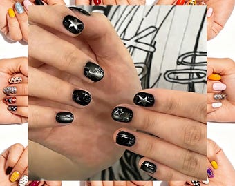 Unhas postiças quadradas curtas com estrelas pretas e prateadas, estilo gótico brilhante e arrojado.