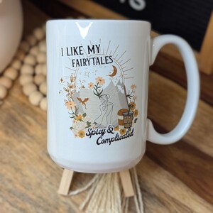 May include: White ceramic mug with a black and gold design. The mug has a quote that reads "I like my fairytales spicy & complicated".