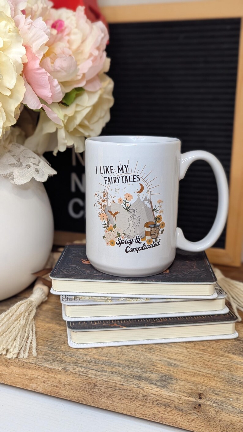 May include: White ceramic mug with a black and brown illustration of a mountain scene with the text "I like my fairytales spicy & complicated".