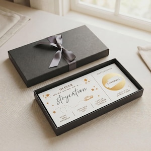 Puede incluir: Una caja de regalo rectangular negra con una cinta gris, que contiene una tarjeta blanca con estrellas doradas. El texto dice: OLIVER WE'RE GOING ON A... strycation, 20TH-20TH AUGUST 2037, HAPPY 30TH BIRTHDAY, LOTS OF LOVE FROM SOPHIE X, y un círculo dorado para rascar.