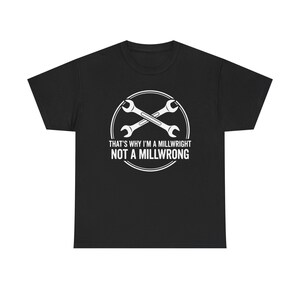 Op de afbeelding: Zwart T-shirt met een witte afbeelding van gekruiste moersleutels in een cirkel. De tekst luidt "THAT'S WHY I'M A MILLWRIGHT NOT A MILLWRONG". Het shirt is gemaakt van zacht materiaal en heeft een ronde hals.