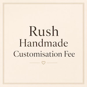 Puede incluir: Fondo crema con borde marrón y texto. El texto dice "Rush Handmade Customisation Fee" en una fuente serif. Un pequeño corazón está centrado debajo del texto.