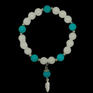 May include: A beaded bracelet featuring alternating white and turquoise round beads separated by small silver-toned metal spacers. A dangling charm hangs from the center, consisting of a single turquoise bead topped with a silver-toned metal feather.