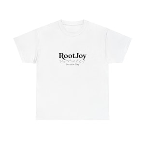 Può includere: Una t-shirt bianca a maniche corte con una grafica nera sul petto. La grafica mostra il testo RootJoy in un carattere serif in grassetto, posizionato sopra una sottile illustrazione di vite decorativa e il testo Mexico City sotto.