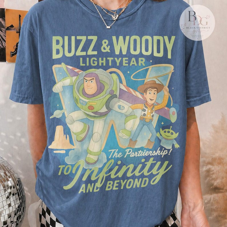 May include: Blue t-shirt featuring Buzz Lightyear and Woody from Toy Story. The graphic includes the text "Buzz & Woody Lightyear" and "To Infinity and Beyond". The design has a vintage, distressed look.