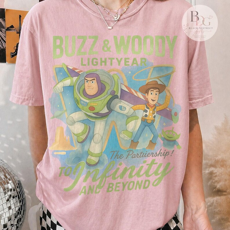 May include: Pink t-shirt featuring Buzz Lightyear and Woody from Toy Story. The graphic includes the text "BUZZ & WOODY LIGHTYEAR" and "TO INFINITY AND BEYOND". The design also includes the phrase "The Partriership!"