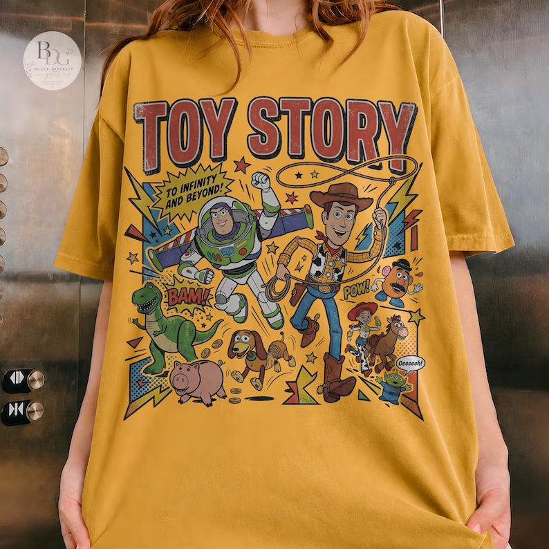 May include: Mustard yellow t-shirt featuring a colorful graphic of Toy Story characters, including Buzz Lightyear and Woody. The text "TOY STORY" is at the top, with "TO INFINITY AND BEYOND!" below. Comic book style design with stars and action words.