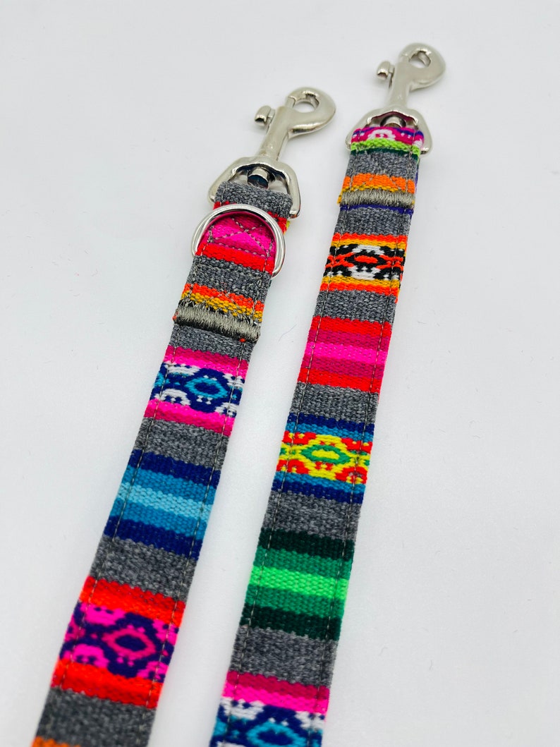 May include: Two colorful dog leashes with silver clips. The leashes have a gray background with multi-colored stripes and geometric patterns.