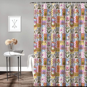 May include: A shower curtain featuring a repeating patchwork pattern of geese wearing pink bows, colorful floral arrangements, and checkered squares in shades of orange, pink, yellow, and blue, suspended from a metal rod with white curtain rings.
