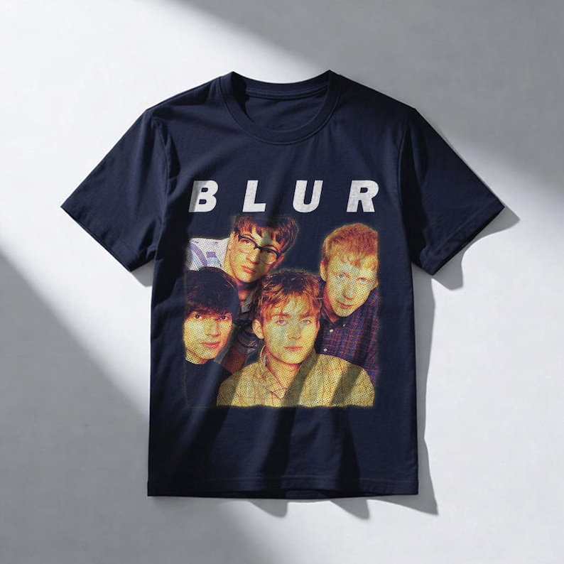 Puede incluir: Camiseta azul marino con la palabra 'BLUR' en letras blancas en bloque sobre una foto de la banda. La imagen es una impresi&oacute;n de estilo vintage.