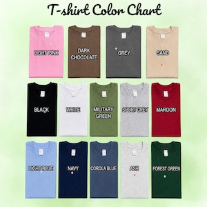 May include: A T-shirt Colour Chart displaying thirteen folded shirts in various colours including light pink, dark chocolate, grey, sand, black, white, military green, sport grey, maroon, light blue, navy, corola blue, ash, and forest green.